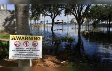 Aviso de alerta ao lado de área inundada após passagem do furacão Ian